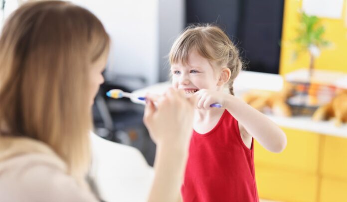Lavare i denti Una donna spiega a una bambina come lavare i denti