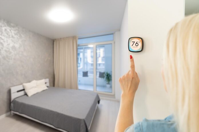 Thermostat smart home domotic control panel on wall for winter house temperature banner panoramic. Energy saving hand touching to adjust temperature of heating in living room. Donna imposta la temperatura nella camera da letto