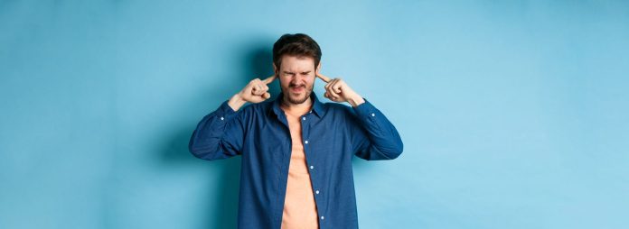 Un uomo si tappa entrambe le orecchie usando il dito indice